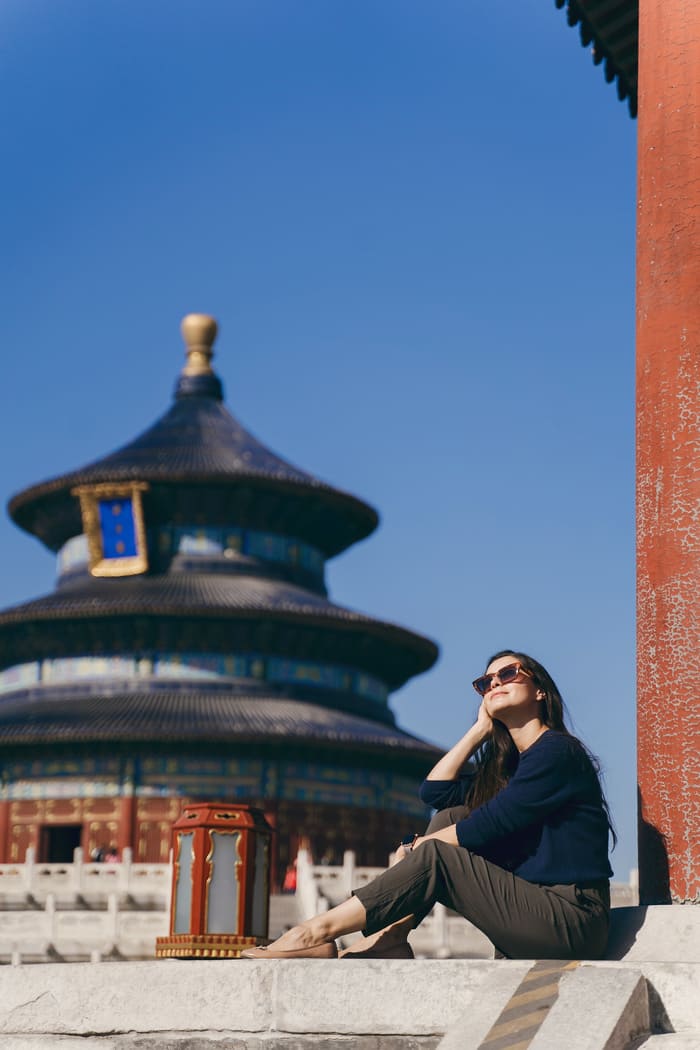 mujer con gafas de sol sentada afuera de un templo de Beijin